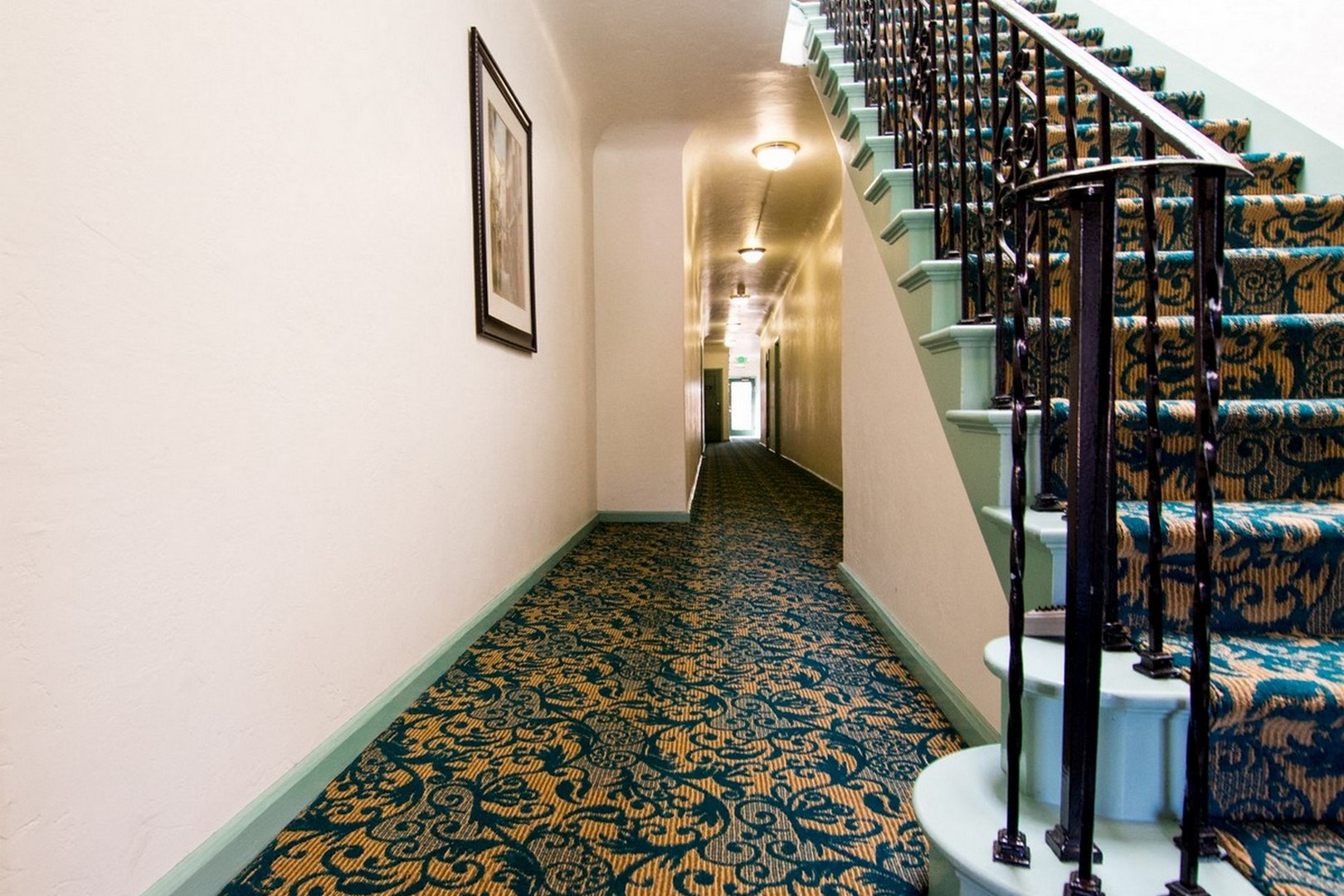 A hallway with a staircase and a picture on the wall.